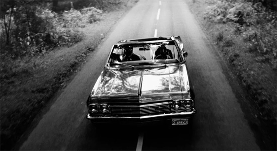 A black and white photo of two people in the back seat of a car.