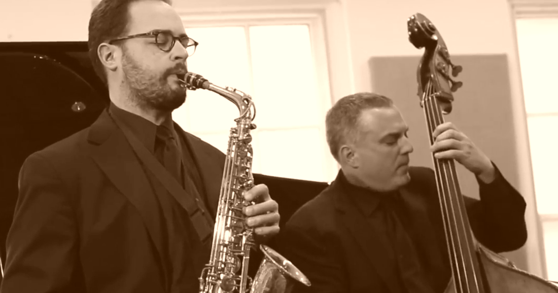 A man holding a saxophone in front of another man.